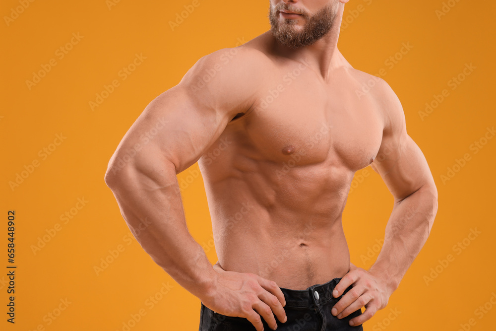 Obraz premium Muscular man showing abs on orange background, closeup. Sexy body