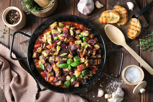 Delicious ratatouille in baking dish served on wooden table, flat lay
