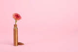 Bullet cartridge case and beautiful chrysanthemum flower on pink background, space for text