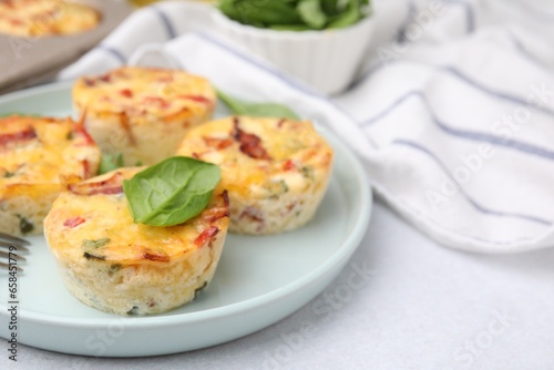 Freshly baked bacon and egg muffins with cheese on light gray table, closeup. Space for text