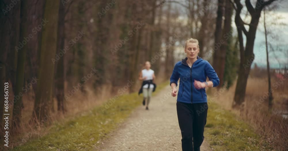 Female athletes jogging by trees in garden Female athletes jogging by trees in garden