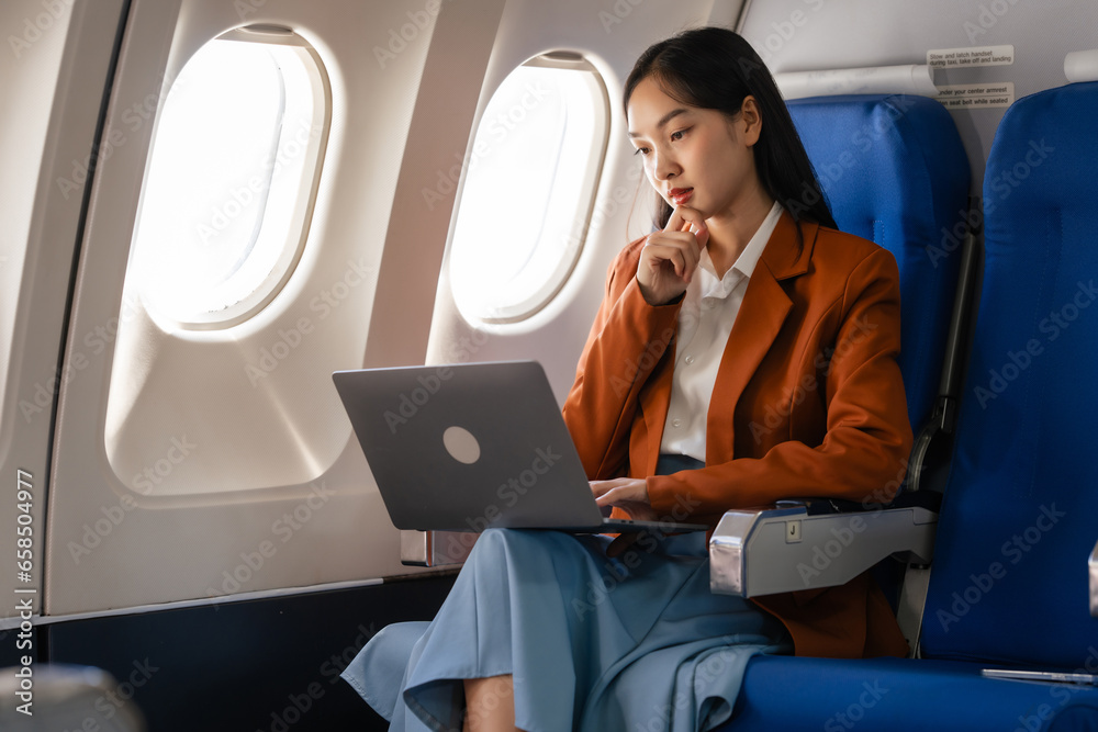 using laptop computer, Elegantly dressed brown suit Asian chinese japanese people businesswoman immersed in work, comfortably seated onboard, capturing the merging worlds of corporate hustle using laptop computer, Elegantly dressed brown suit Asian chinese japanese people businesswoman immersed in work, comfortably seated onboard, capturing the merging worlds of corporate hustle