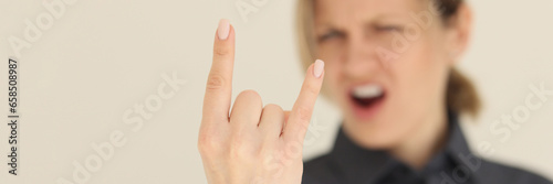 Blurry screaming woman shows horns gesture with fingers photo