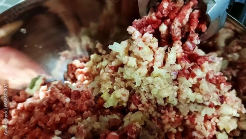 An electric meat grinder grinds beef and pork in the kitchen in daylight. Preparation of minced meat in an electric meat grinder
