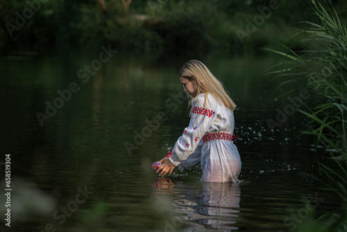 Fototapeta Naklejka Na Ścianę i Meble -  Portrait of a young beautiful blonde girl near a pond.