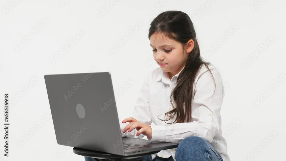 Idea concept. A cute little girl in front of a laptop experiences emotions from an idea or solution to a problem, the girl uses a computer for distance learning on a light background. Idea concept. A cute little girl in front of a laptop experiences emotions from an idea or solution to a problem, the girl uses a computer for distance learning on a light background.