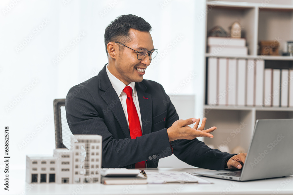 Agent presents contracts for property purchase or lease. Businessman asian indian people showcases miniature model home, signifying secure property insurance. Desk scene in a home sales office. Agent presents contracts for property purchase or lease. Businessman asian indian people showcases miniature model home, signifying secure property insurance. Desk scene in a home sales office.