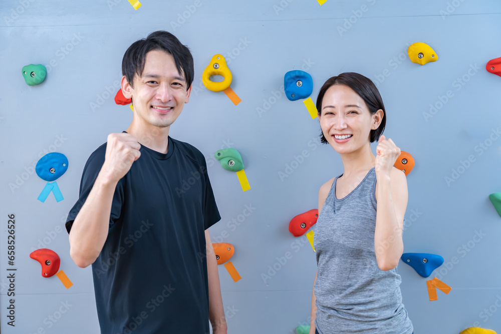 クライミングウォールの前でポーズをとる2人 クライミングウォールの前でポーズをとる2人