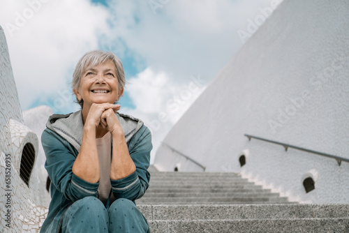 Photography Handsome happy senior woman sitting outdoors on staircases looking away, elderly