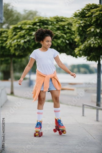 Happy teenage girl rollerblading in a skate park outdoors. A child plays on roller skates.