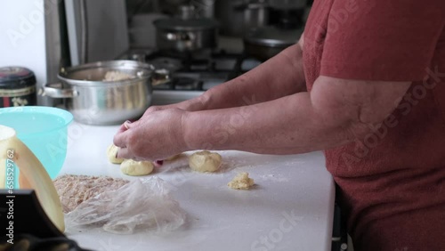 An elderly woman skillfully rolls small balls of dough between her palms. This intimate act illustrates the therapeutic benefits of cooking in older age, aiding both dexterity and mental focus