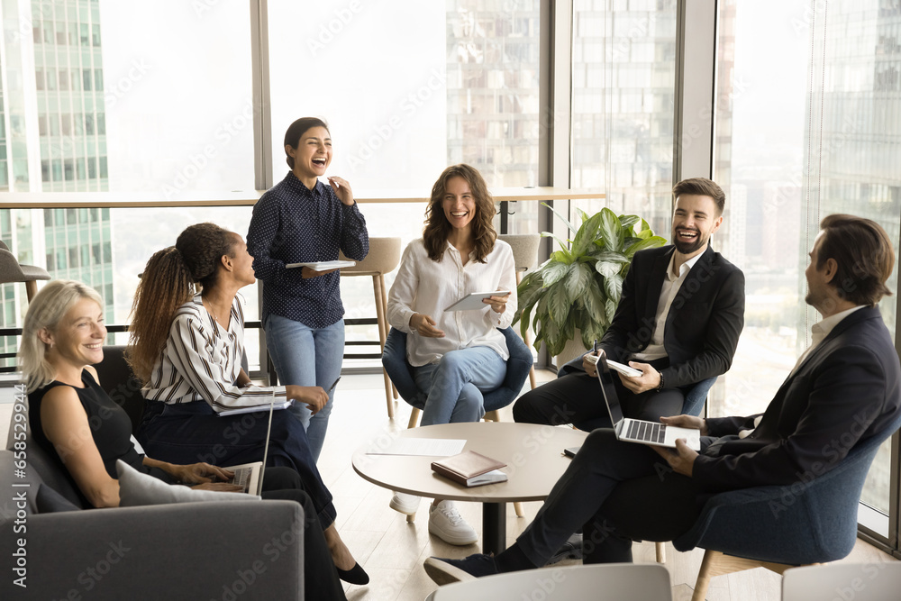 Happy multiethnic business group meeting in office lobby for brainstorming, discussing creative ideas, teamwork strategy, cooperating on work tasks, laughing together