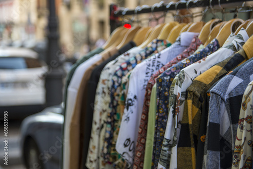 Clothes on the rail on the fashion designer market. Garage sale, reuse the clothes, second hand