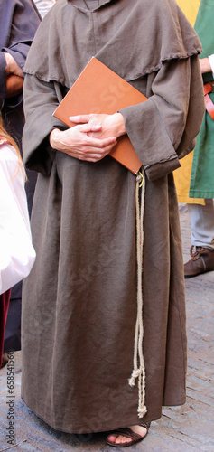Franciscan friar with the brown dress called habit and the rope around his waist with the sacred book on hand photo