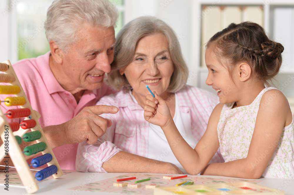 Portrait of happy grandparents with granddaughter using abacus together