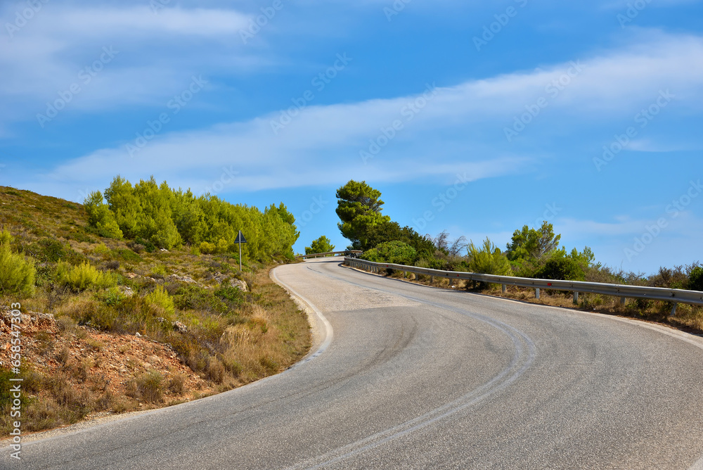 Naklejka premium Empty curvy asphalt road on the green mountain under the blue sky