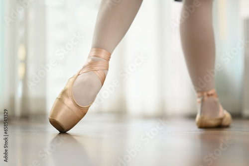 Ballerina feet in pink pointe shoes dancing on wooden floor. People, dance art, education and flexibility concept