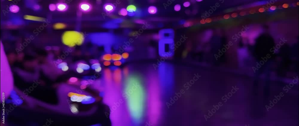 Illuminated bumper car in the evening at the Brilon funfair. The lights and movements can be seen as blurred bokeh. Unknown visitors ride in the scooters. Real-time video in anamorphic format 1.33.
