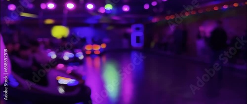 Illuminated bumper car in the evening at the Brilon funfair. The lights and movements can be seen as blurred bokeh. Unknown visitors ride in the scooters. Real-time video in anamorphic format 1.33. photo