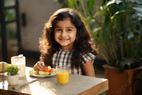 Cute indian little girl eating breakfast at home