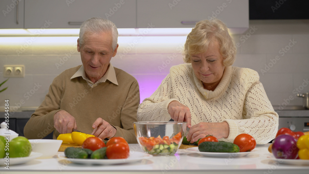 Smiling senior woman and man cutting fresh vegetables in the kitchen, living a healthy lifestyle Smiling senior woman and man cutting fresh vegetables in the kitchen, living a healthy lifestyle