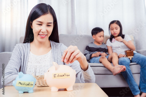 Happy excited asian mother dropping coin into piggy bank Caring mom save money for the future for her kid She invest money collecting coins in piggy bank Family Education saving financial concept