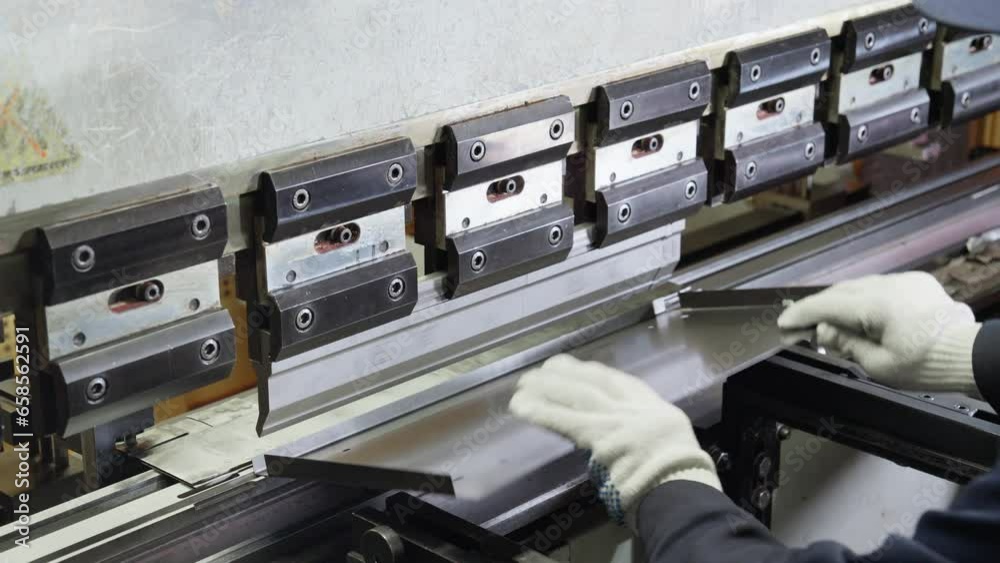 Factory worker puts metal sheet in bending machine. Industrial bending ...
