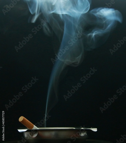 cigarrillo sobre cenicero provocando humo sobre fondo negro
