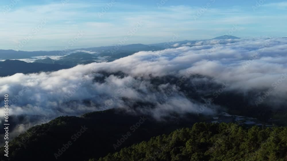 Aerial view over the mountains with sea of fog during morning sunrise in blue sky. Sea of clouds around mountain peaks at sunrise. Unseen travel in Northern Thailand Aerial view over the mountains with sea of fog during morning sunrise in blue sky. Sea of clouds around mountain peaks at sunrise. Unseen travel in Northern Thailand