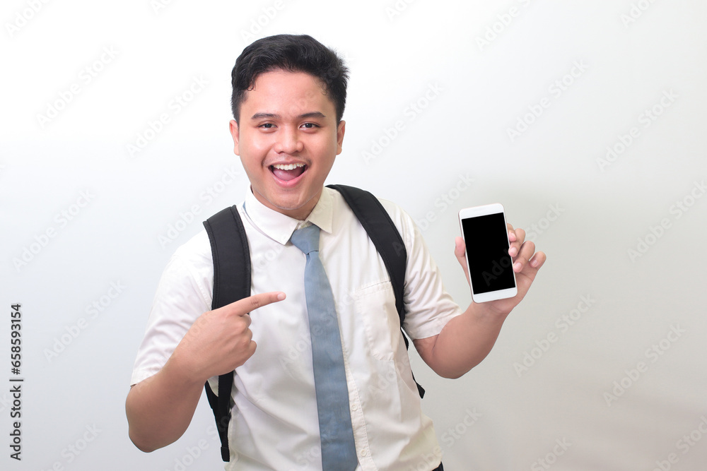 Indonesian senior high school student wearing white shirt uniform with gray tie showing and presenting blank screen mobile phone. Isolated image on white background Indonesian senior high school student wearing white shirt uniform with gray tie showing and presenting blank screen mobile phone. Isolated image on white background