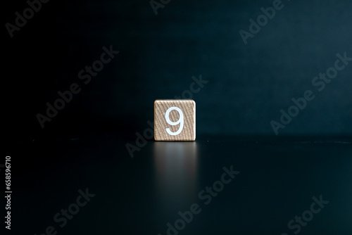 Wooden block written "9" with a Black background.