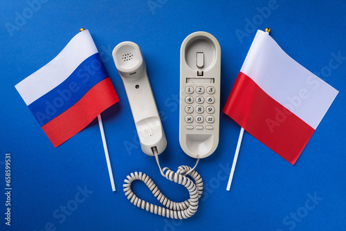 Old telephone and two flags on a blue background, concept of telephone conversations between Poland and Russia