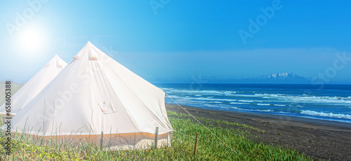 White glamping tents against the backdrop of the Pacific Ocean on the Kamchatka Peninsul