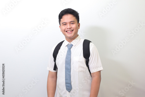 Indonesian senior high school student wearing white shirt uniform with gray tie smiling and looking at camera. Isolated image on white background photo