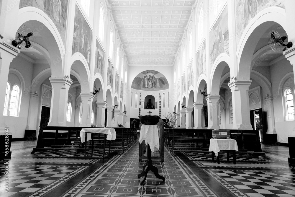 Interior de igreja católica de arquitetura clássica com arco e bancos de madeira.  - obrazy, fototapety, plakaty 