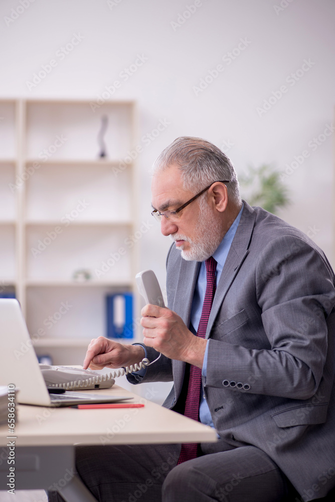 Old male employee working in the office Old male employee working in the office