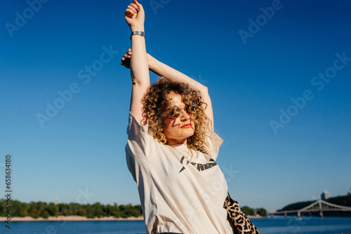 Relaxed girl standing with hands up to the blue sky and dreaming 