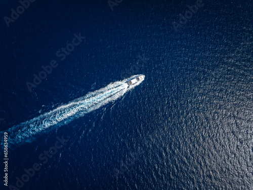 High aerial view of a luxury yacht traveling over the sparkling ocean