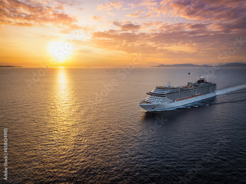 Panoramic aerial view of a cruise ship traveling over the ocean during golden summer sunset time © moofushi