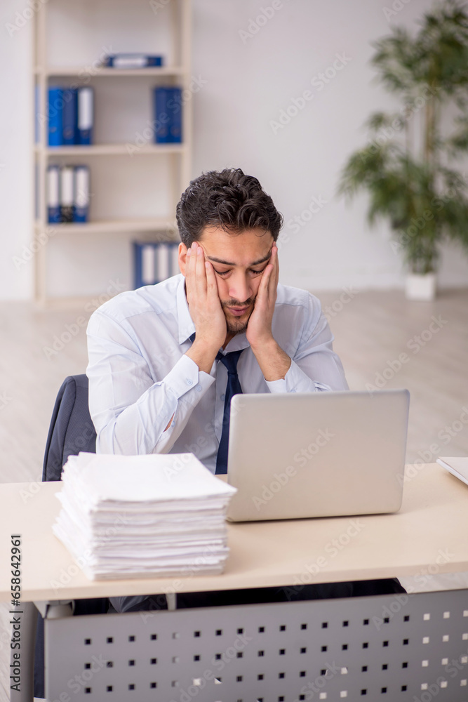 Young male employee and too much work in the office Young male employee and too much work in the office