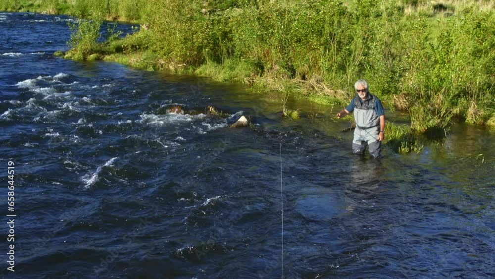 Man Fly Fishing In Stream - High, wide shot Man Fly Fishing In Stream - High, wide shot
