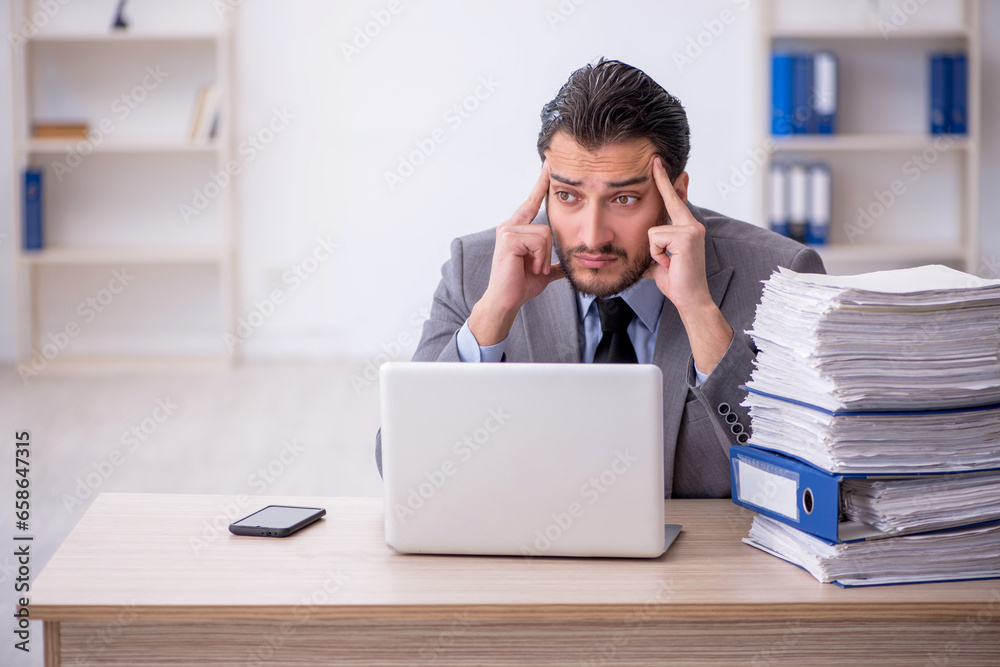 Young male employee and too much work in the office Young male employee and too much work in the office