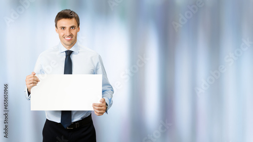 Concept ad photo - business man professional manager wear confident shirt, necktie. Standing businessman holding, showing empty white banner sign board, office background.