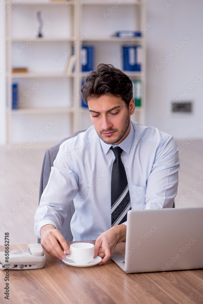 Young male employee drinking coffee during break Young male employee drinking coffee during break