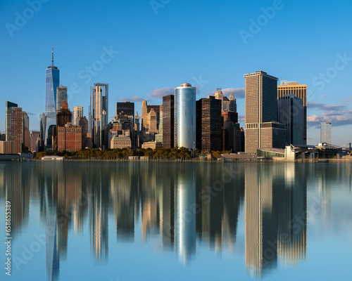 Lower manhattan cityscape, Panoramic landscape with water reflection obut New York city USA. Clear blue sky and amazing mirrored skyscrapers.