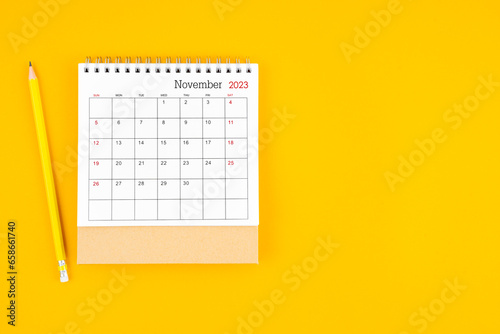 November2023 desk calendar and wooden pencil on yellow background. Time planning, day counting and holidays.