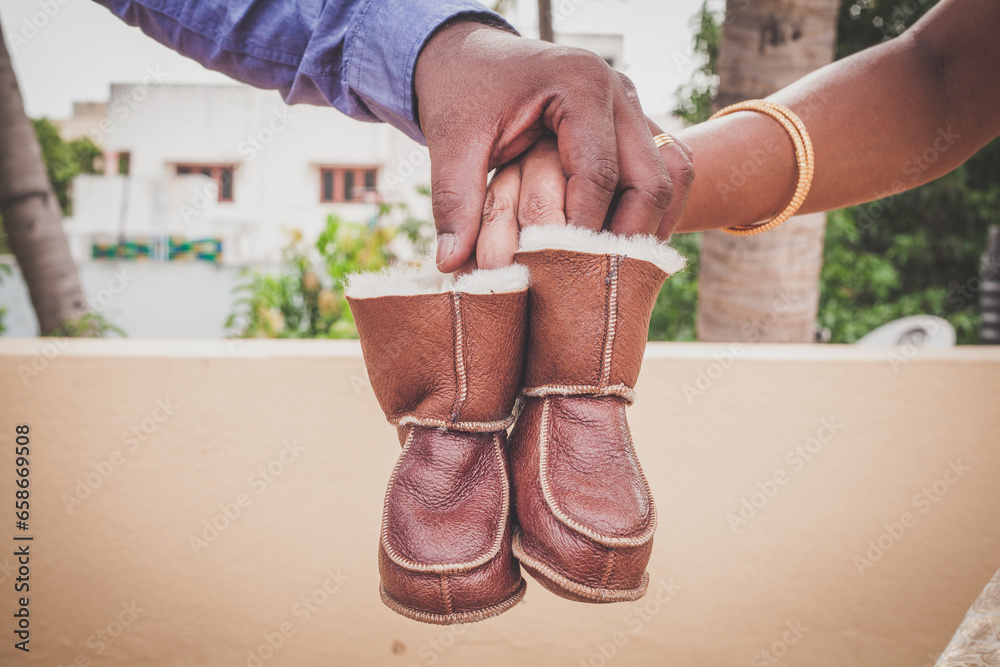 close up of couple hands holding a pair of baby boots