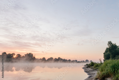 Beautiful landscape with a river and reflection  thick fog at dawn. Lake in the early morning in thick fog
