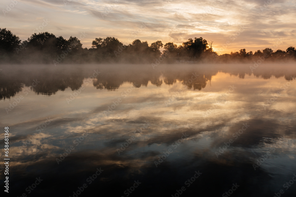 Fototapeta premium Beautiful landscape with a river and reflection, thick fog at dawn. Lake in the early morning in thick fog