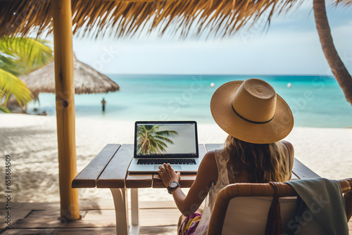 Back view of woman in hat working on laptop at table on tropical beach, Digital nomad’s lifestyle, Remote job and teleworking concept, Vacation Leave, Travel visa